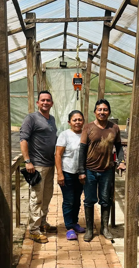 Three people standing together inside the farm's drying house